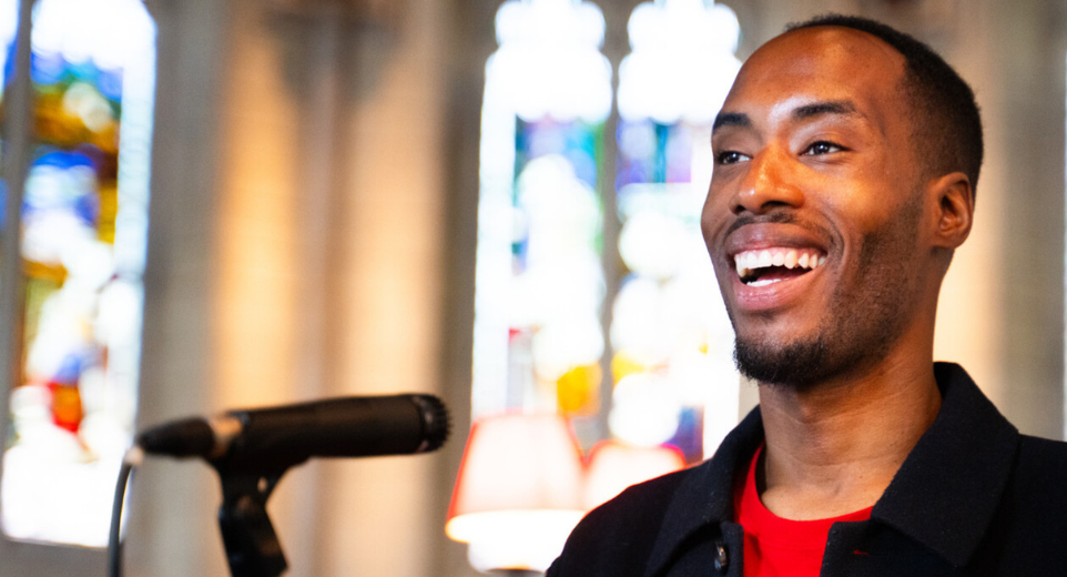 Man wearing a Christian Aid tshirt giving a talk at the front a church